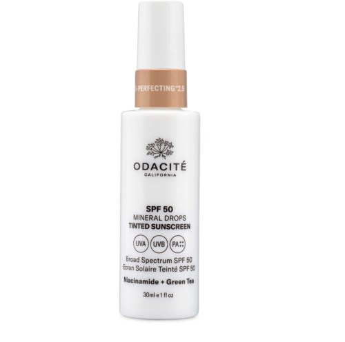 En hvit flaske med Odacité mineralgrunnlag med SPF 50, niacinamid og grønt te, med bredspektret beskyttelse.