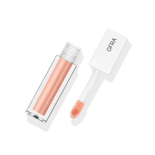 Een heldere lipglossfles met een perzikkleurige applicator en de merknaam OFRA op de dop.