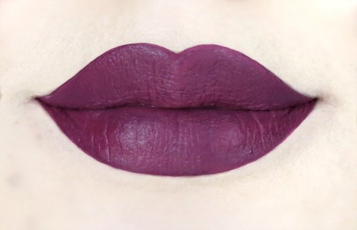Närbild av läppar med lila/magenta läppstift på ljus hud.