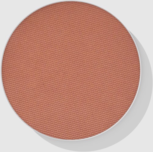 A round makeup blush with a soft peach color and textured surface.