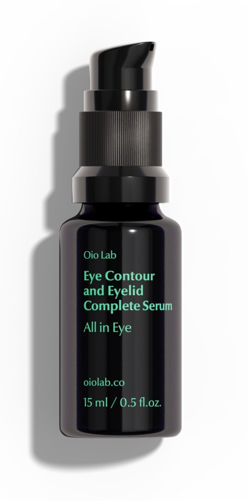 Een kleine zwarte fles met pomp, gelabeld voor oogcontour en ooglidserum, bevat 15 ml. Schaduwen liggen ernaast.