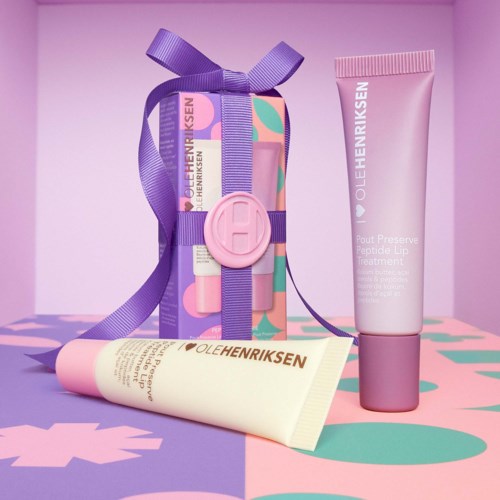 Three Ole Henriksen skincare products: a cream tube, a pink lip treatment, and a gift box with purple ribbon and seal.