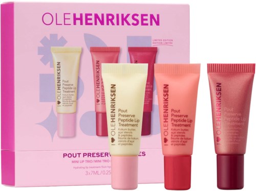Set of four small tubes of Ole Henriksen lip treatment in pink, beige, and red packaging with a pink box in the background.