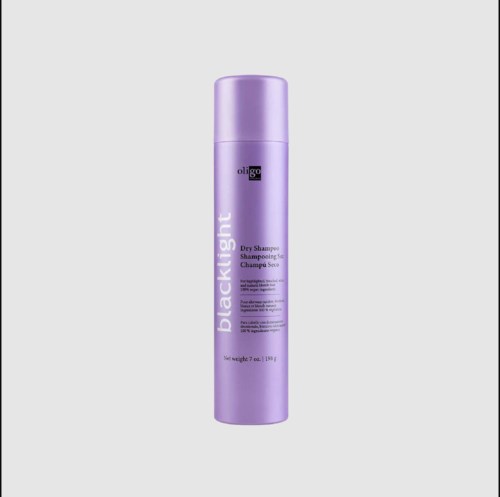 Lilla flaske med tørt shampoo med sort og hvid mærkat står oprejst.