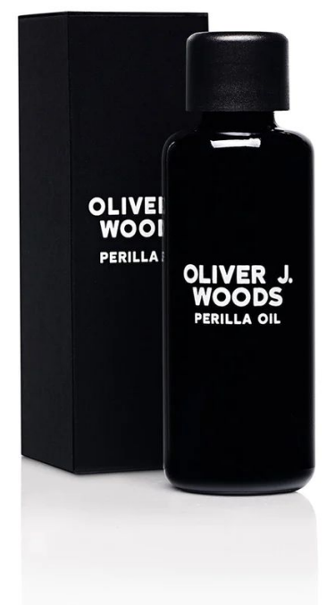 Czarna butelka Oliver J. Woods Perilla Oil z czarnym pudełkiem za nią.