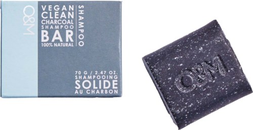 Vegansk kulshampoo bar i emballage, med baren synlig ved siden af, mærket "OUM".