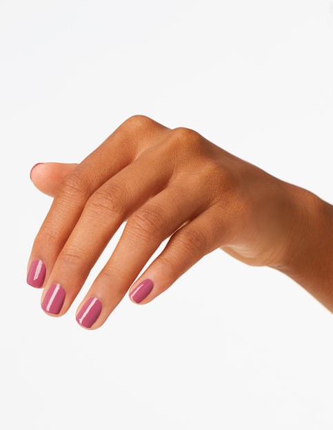 En hand med välskötta naglar målade rosa, fingrar något böjda, mot en enkel bakgrund.