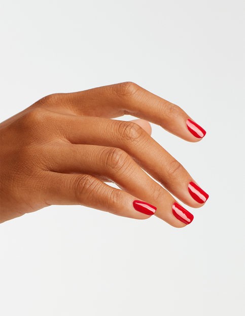 En hand med röd- och vitrandig nagellack mot en enkel bakgrund.