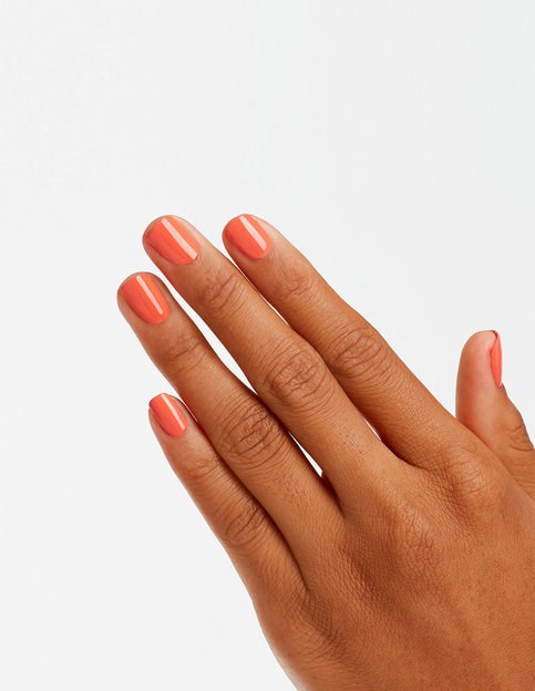 Hand med snyggt målade orange naglar mot en enkel bakgrund.