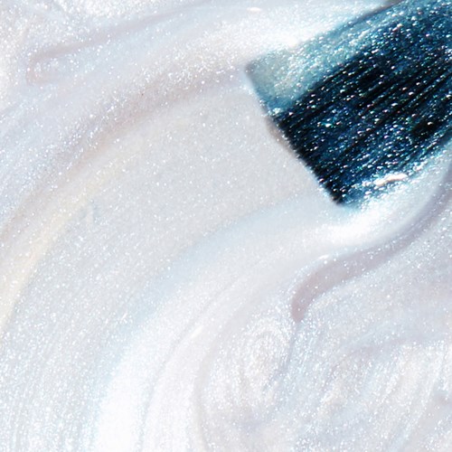 Et nært bilde av en børste som sprer glitrende hvit maling eller glitter, og skaper en jevn, glitrende overflate.