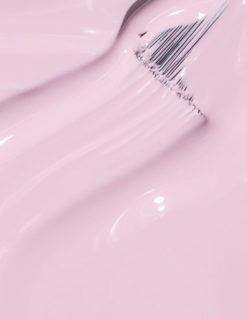 En makeupborste doppad i rosa kräm eller färg, skapar en slät, glänsande yta.