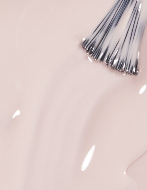 Eine Nagelbürste mit Metallborsten auf hellem rosa Hintergrund, wahrscheinlich zum Malen oder Reinigen von Nägeln.