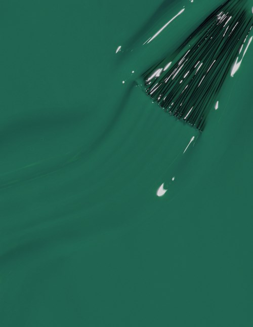 A green surface with black liquid paint and a tool spreading the paint around.