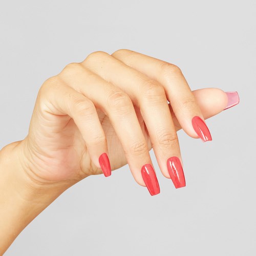 En hånd med lange, blanke rosa negle vises mod en grå baggrund.