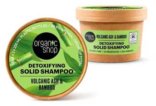 En grön etikett på en brun behållare visar detoxifierande fast schampo med vulkanaska och bambu.