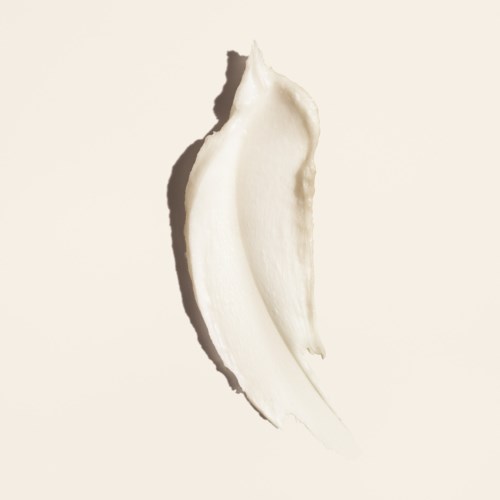 Ett streck av vit kräm eller lotion på en enkel beige bakgrund, med skuggor som framhäver texturen.