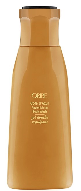 En lang, gullfarget flaske med Oribe Côte d'Azur Replenshing Body Wash med svart lokk.