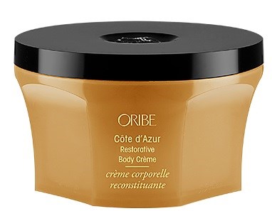 En boks med Oribe kroppskrem, gullfarget med svart lokk, merket 'Côte d’Azur Restorative Body Crème.'
