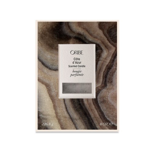 A scented candle package labeled "ORIBE Côte d'Azur" with a marble background design.