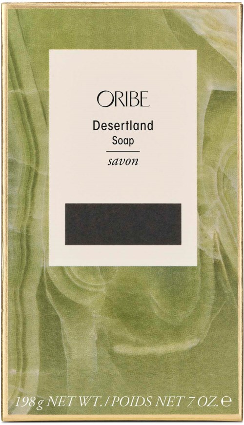 En såpeeske merket 'Oribe Desertland Soap' med grønn og hvit design, vekt og svart område for strekkode.