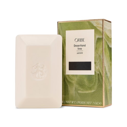 En såpestykke med en boks ved siden av merket "Oribe Desertland Soap" og en dekorativ design.