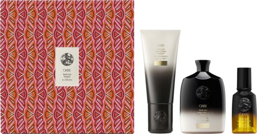 Een geschenkdoos met een patroonomslag, drie zwarte, witte en gele flessen, vermoedelijk verzorgingsproducten of parfum.