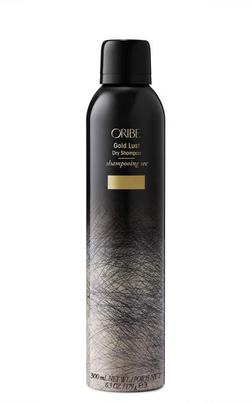 Svart schampoflaska med guldmärkning, märkt 'ORIBE Gold Lust Dry Shampoo,' och en texturerad silver och svart design.
