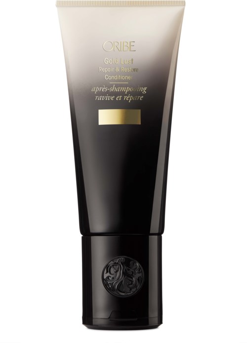 En svart och guldig tub märkt ORIBE Gold Lust Repair & Restore Conditioner med en logga nära botten.