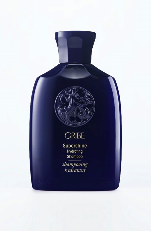 En mørk blå flaske med Oribe Supershine Hydrating Shampoo og et sølvmerke på forsiden.