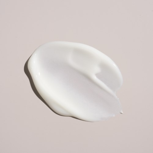 A white, curved dollop of cream or lotion on a plain background.