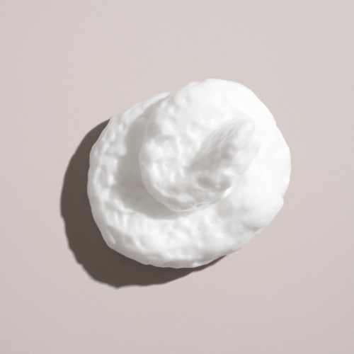 A white, fluffy object with a round shape sits on a light background, casting a small shadow.