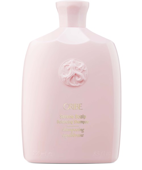 A light pink shampoo bottle with a raised emblem and gold text, labeled as Oribe Serene Scalp Balancing Shampoo.
