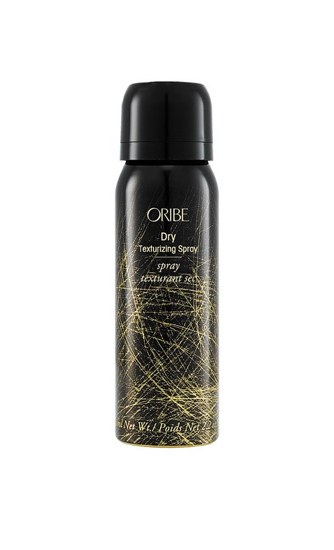 En svart sprayflaska med gyllene linjer och text, märkt Oribe Dry Texturizing Spray.