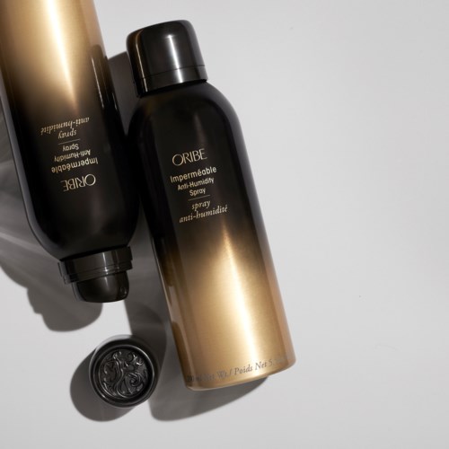 To sprayflasker i svart og gull merket ORIBE Anti-Humidity, med svart lokk og liten beholder i nærheten.