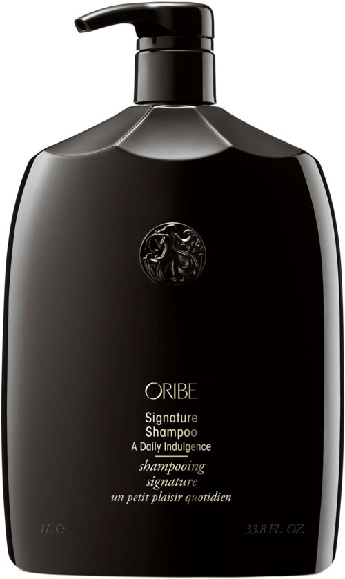 En svart flaske med pumpe, merket Oribe Signature Shampoo, elegant design, med gull og hvit tekst.