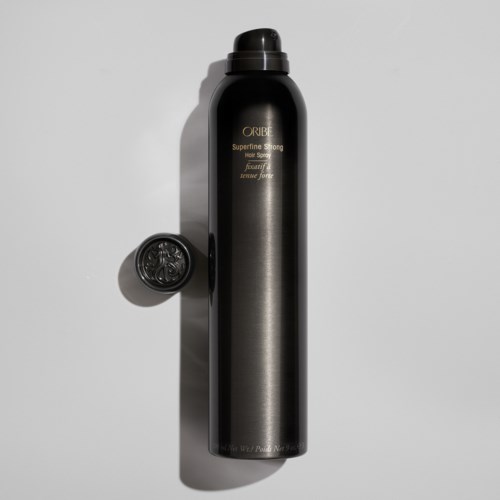Długa czarna butelka spray do włosów z nakrętką, oznaczona "Oribe" i "Superfine Strong" na białym tle.