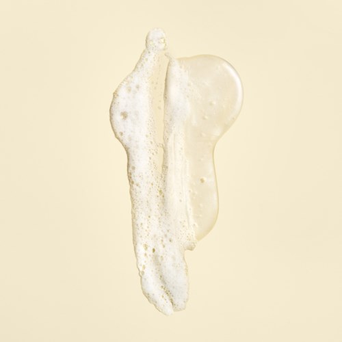 A think, creamy, white substance with bubbles on a beige background.