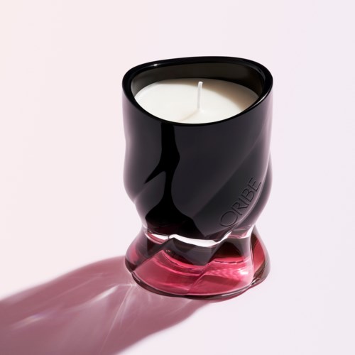 En svart og rosa lysestake med et hvitt lys inni, som kaster en skygge på en lys overflate.
