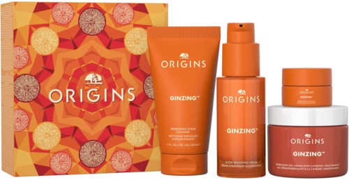 A set of orange skincare products from Origins, including a box, lotion, spray, and cream, with bright orange packaging.