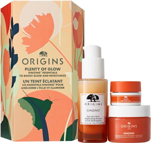 Three skincare products in orange and white containers beside a floral box, promoting glowing and brightening effects.