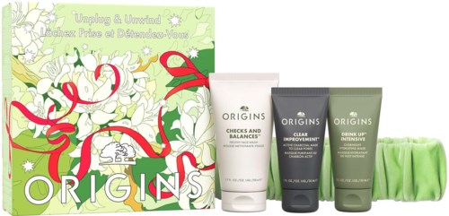Origins gift set with skincare products in white, black, and green tubes in front of a holiday-themed box.
