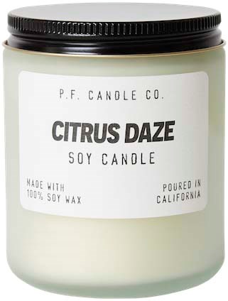 Een kaars met het label Citrus Daze, gemaakt met sojawas, gegoten in Californië, in een pot met zwarte deksel.