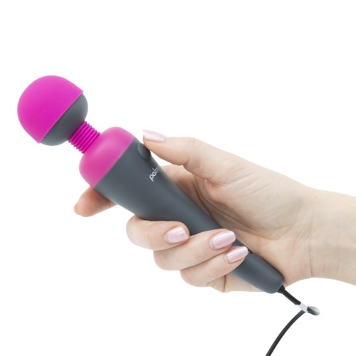 A hand holds a pink and gray massage device with a round head and a cord.
