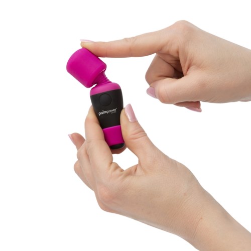Small pink and black massage device held by a person, used for muscle relaxation.