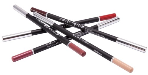Flere makeup-stifter i forskellige nuancer ligger krydset over hinanden på en sort baggrund.