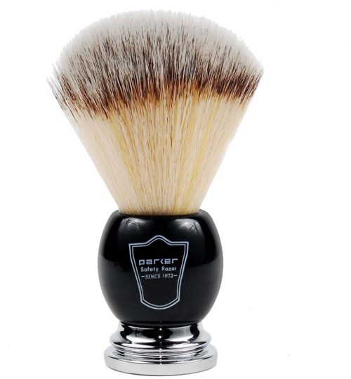 En barberbørste med svart håndtak og myke, brune og hvite bust. Håndtaket har en skjoldlogo.