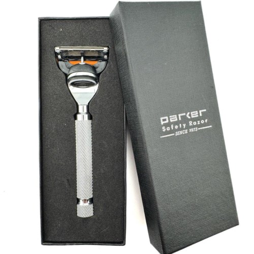 En säkerhetsrakhyvel med metallhandtag i en box märkt 'Parker Safety Razor'.