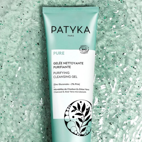 En grøn tube med Patyka Purifying Cleansing Gel på en grøn tekstureret baggrund.