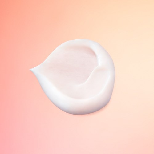 En vit, böjd keramikskål med en liten pip, mot en rosa och orange gradientbakgrund.