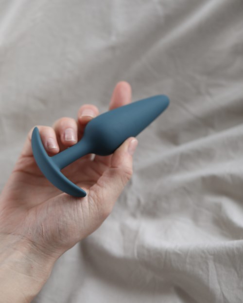 A hand holding a blue, curved device that resembles a small, smooth tool or toy.